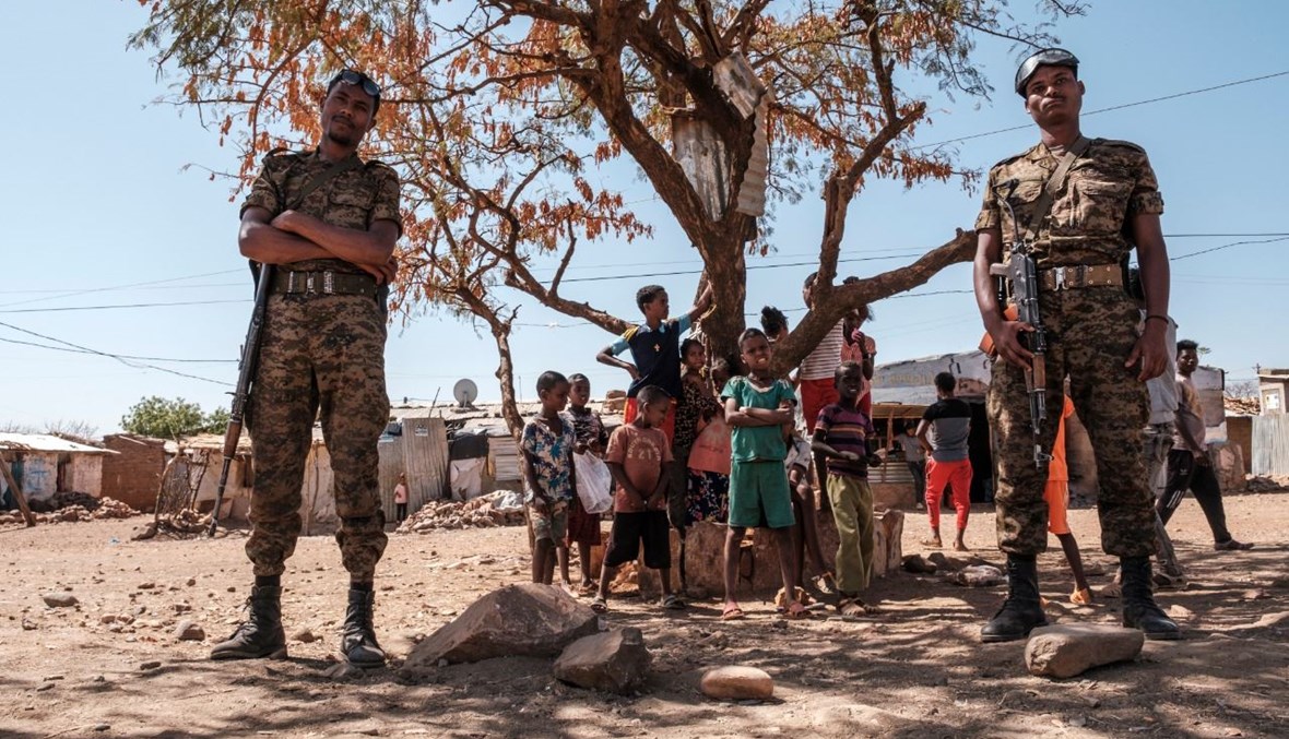 جنود من الجيش الإثيوبي يقفون بالقرب من أطفال في مخيم ماي عيني للاجئين في إثيوبيا (30 ك2 2021، أ ف ب). 