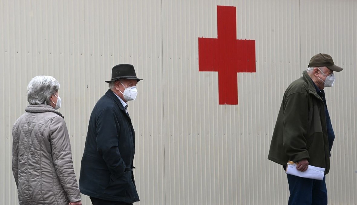 مسنون ينتظرون بالصف بجوار الصليب الأحمر امام مركز تطعيم في فريسينغ جنوب ألمانيا (2 شباط 2021، أ ف ب).