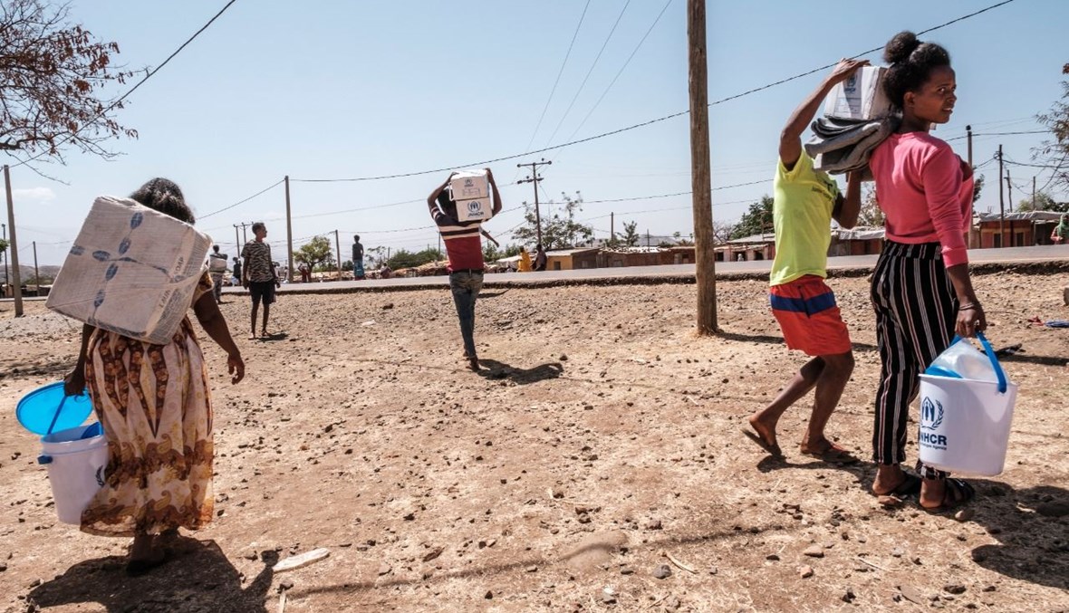 لاجئون إريتريون يحملون مساعدات وزعتها مفوضية الأمم المتحدة السامية لشؤون اللاجئين في مخيم ماي عيني للاجئين في إثيوبيا (في 30 ك2 2021، أ ف ب).