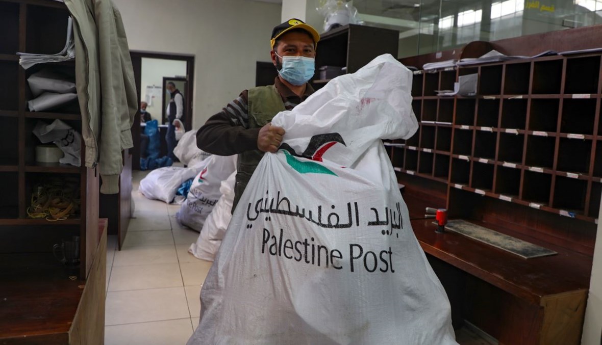 موظف في البريد الفلسطيني يحمل كيسا في مكتب بريد في مدينة نابلس بالضفة الغربية (7 شباط 2021، أ ف ب).