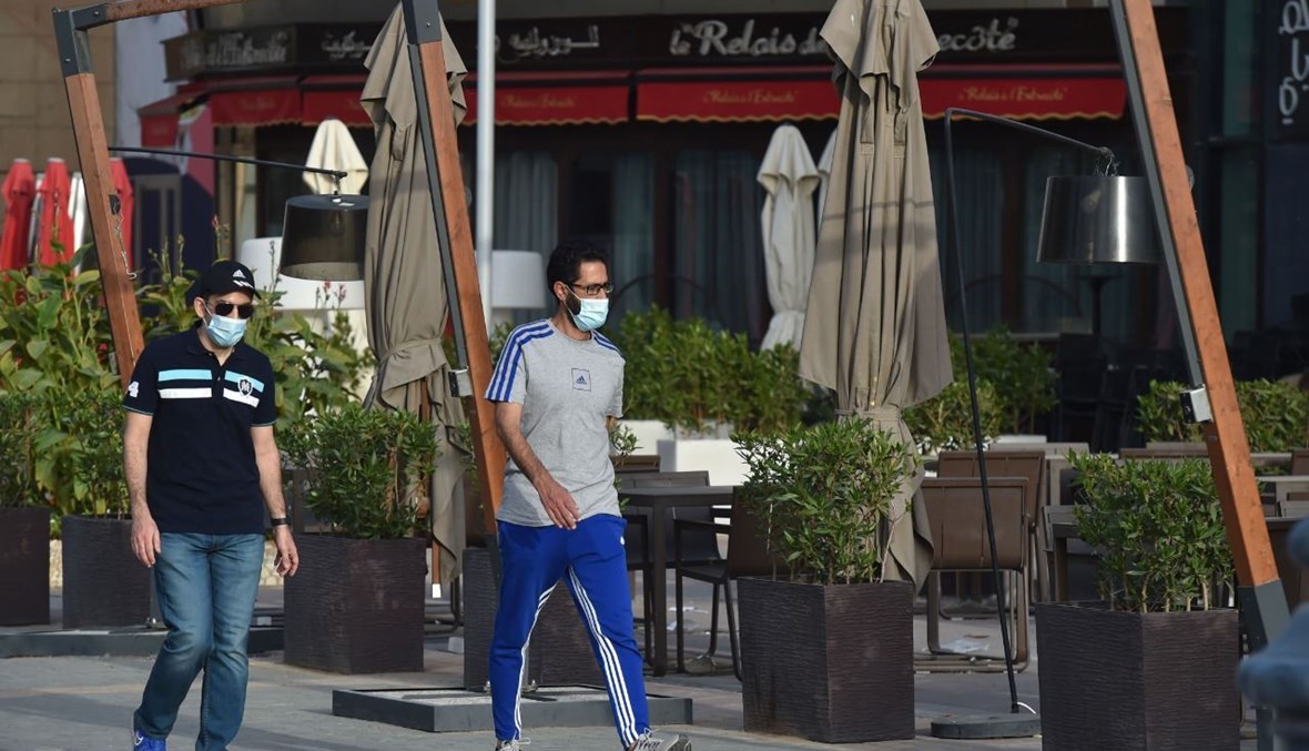 رجلان يمران بالقرب من مطعم مغلق في الرياض (5 شباط 2021، أ ف ب). 