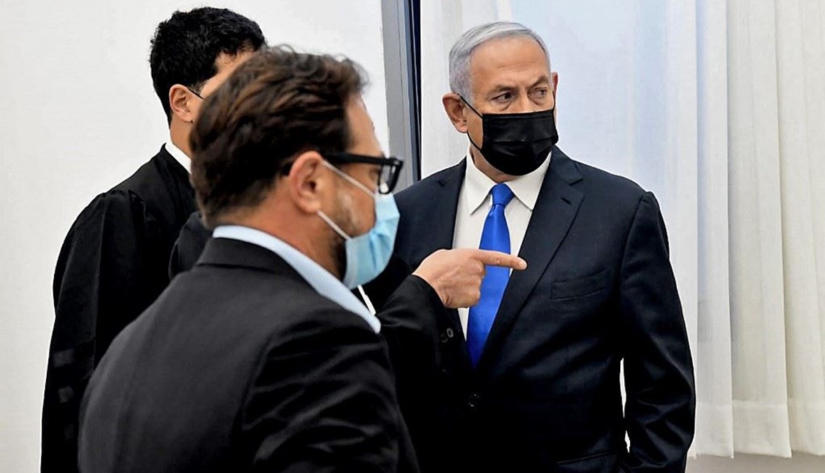 رئيس الوزراء الاسرائيلي بنيامين نتنياهو –الى اليمين-يتحدث إلى محاميه قبل مثوله أمام المحكمة في القدس أمس. (أ ف ب)