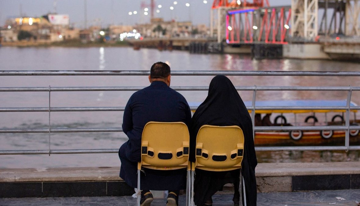 ثنائي جلس عند ضفاف نهر شط العرب في مدينة البصرة جنوب العراق (14 شباط 2021، أ ف ب).