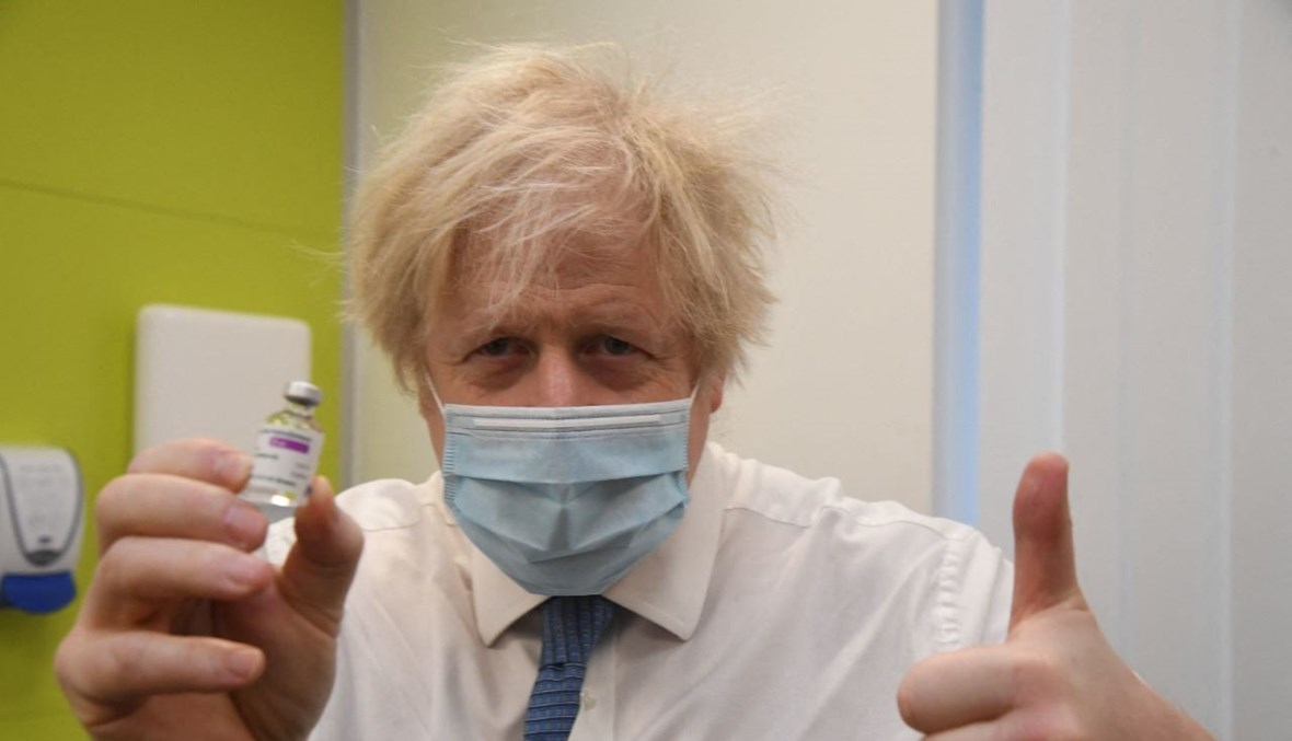 جونسون يحمل قارورة من لقاح استرازينيكا/اكسفورد خلال زيارته مركز تطعيم في أوربينغتون جنوب شرق لندن (15 شباط 2021، أ ف ب). 