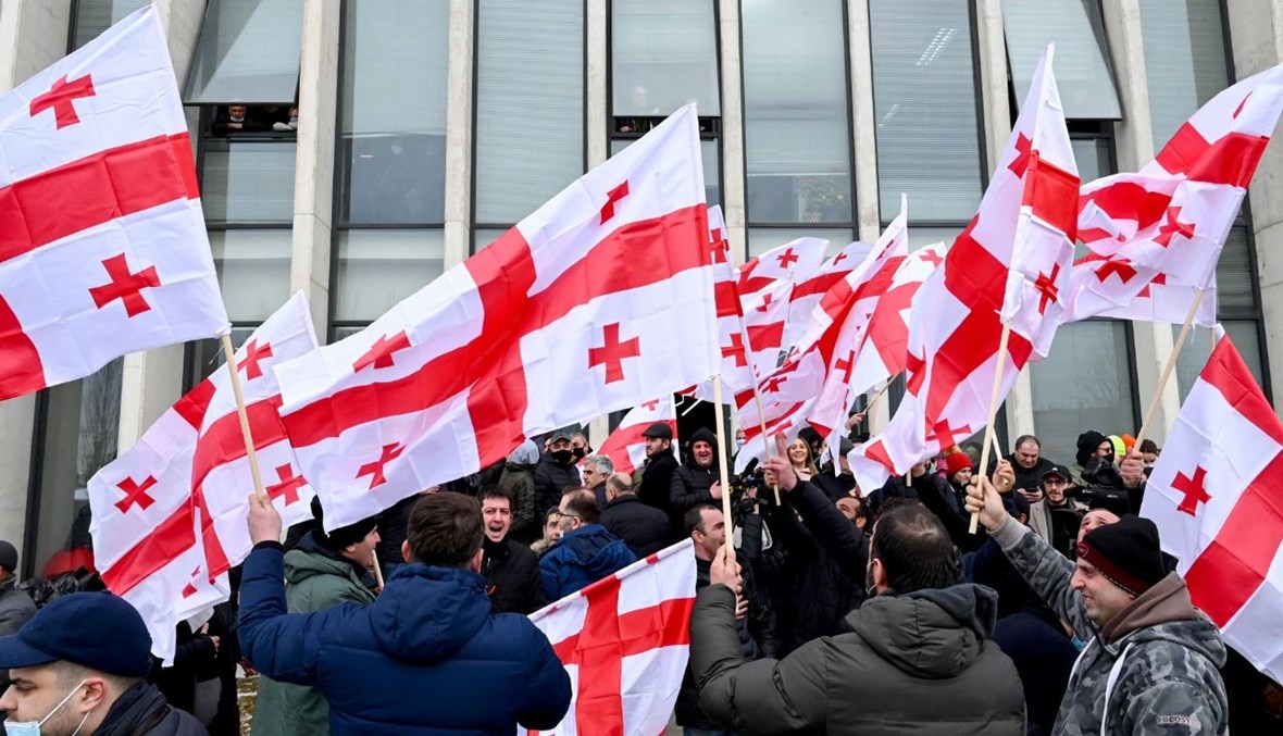 أنصار المعارضة الجورجية يلوحون بالأعلام أمام مقر الحركة الوطنية المتحدة في تبليسي، عقب إعلان غاخاريا استقالته (18 شباط 2021، أ ف ب).
