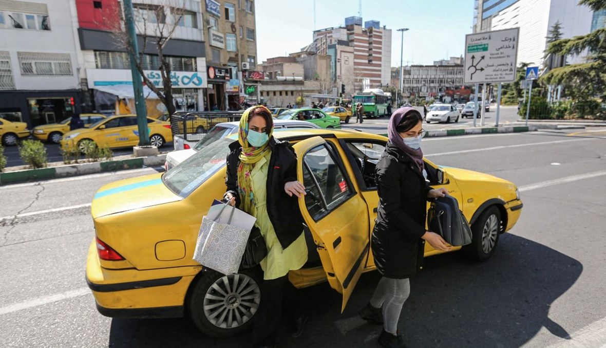 امرأتان تنزلان من سيارة أجرة في وسط طهران (21 شباط 2021، أ ف ب).