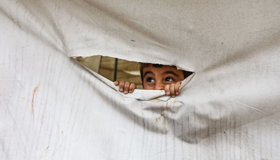 طفل ينظر من خلال ثقب بخيمة في مخيم للنازحين في قرية نيارة في الريف الشمالي لحلب (1 شباط 2021، أ ف ب).