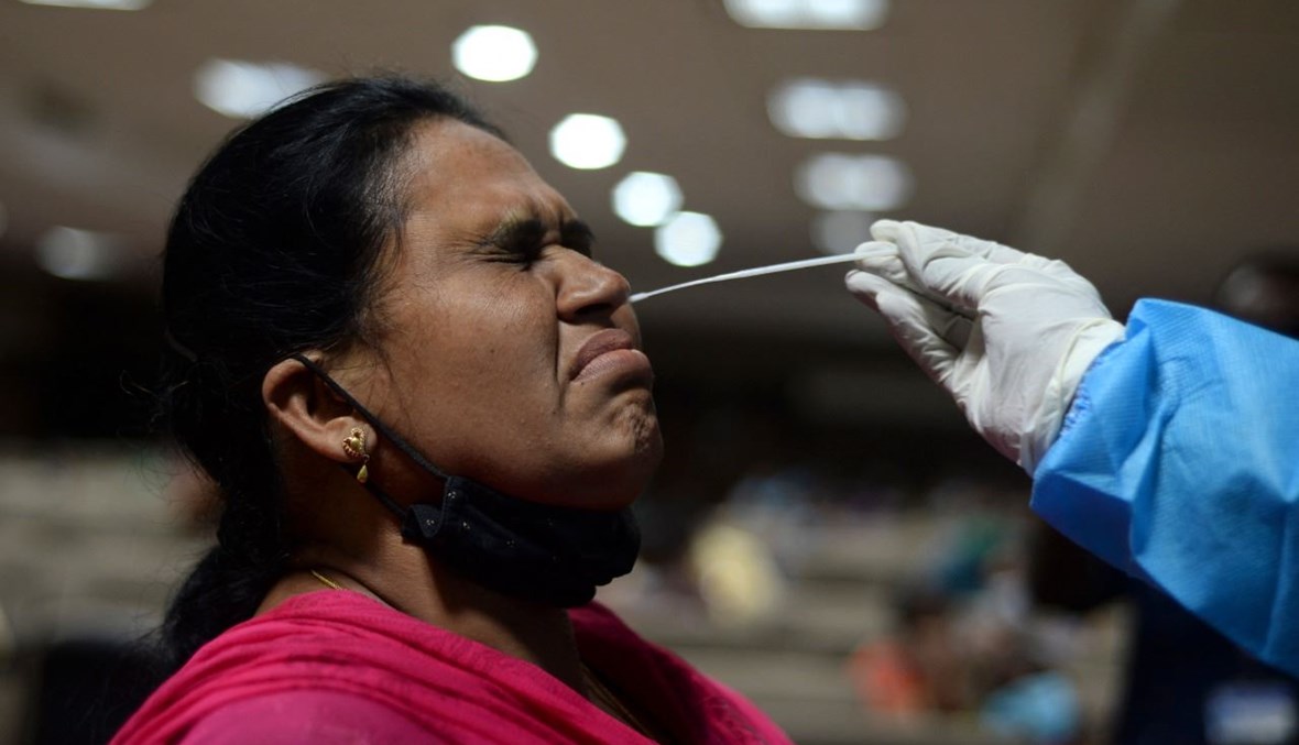 عامل صحي يأخذ مسحة أنفية من امرأة في تشيناي بالهند (22 شباط 2021، أ ف ب). 