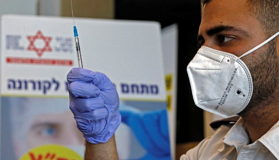 عامل صحّي إسرائيلي يحضّر جرعة من لقاح "فايزر" خلال حملة التلقيح (أ ف ب).