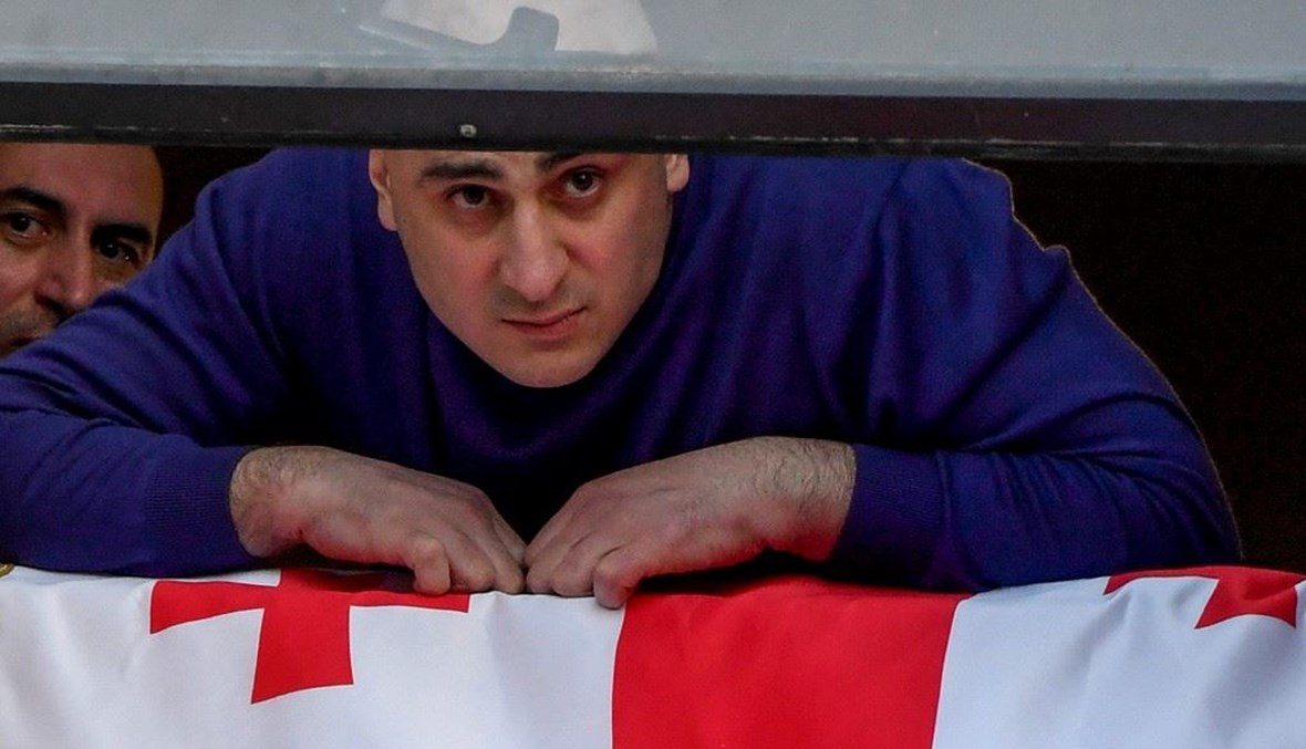 زعيم "الحركة الوطنية المتحدة" الجورجية المعارضة نيكا ميليا يطل من نفاذة مقر الحركة تيبليسي قبيل اعتقاله أمس.   (أ ف ب)