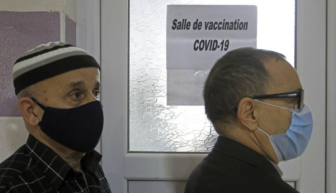 رجلان ينتظران تلقي لقاح كورونا في مركز التطعيم في البليدة جنوب الجزائر العاصمة (30 ك2 2021، أ ب). 