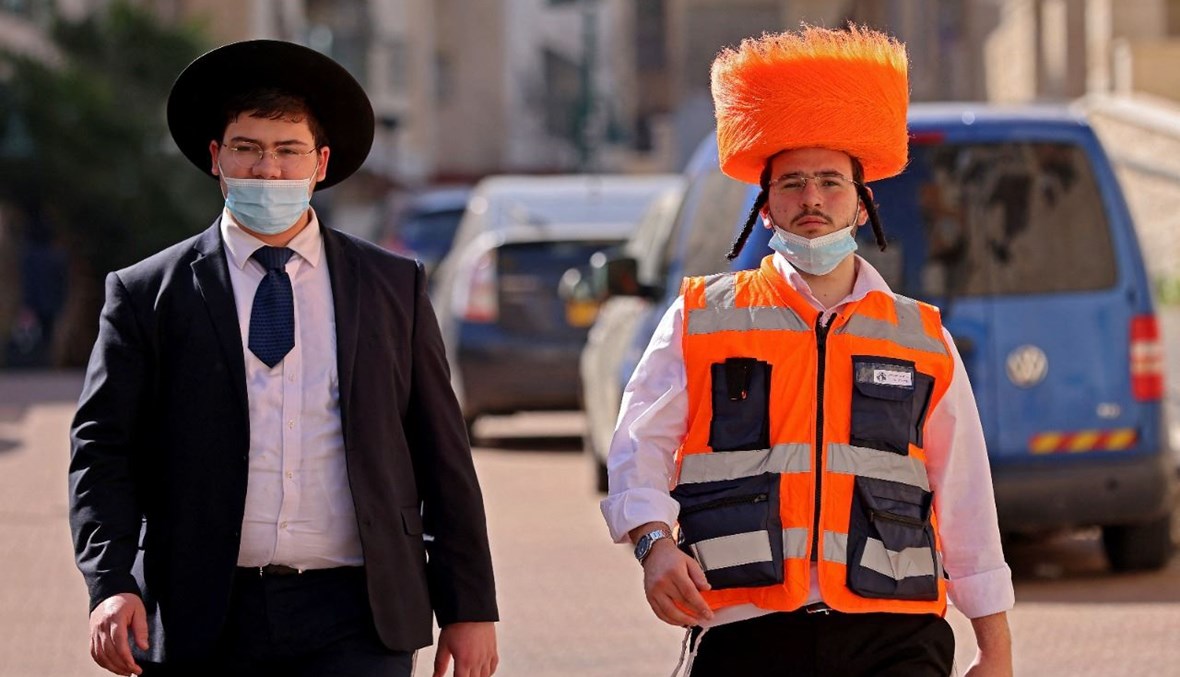 إسرائيليان يرتديان أزياء خاصة بعيد المساخر اليهودي، في حي بني براك الأرثوذكسي المتشدد (26 شباط 2021، أ ف ب).