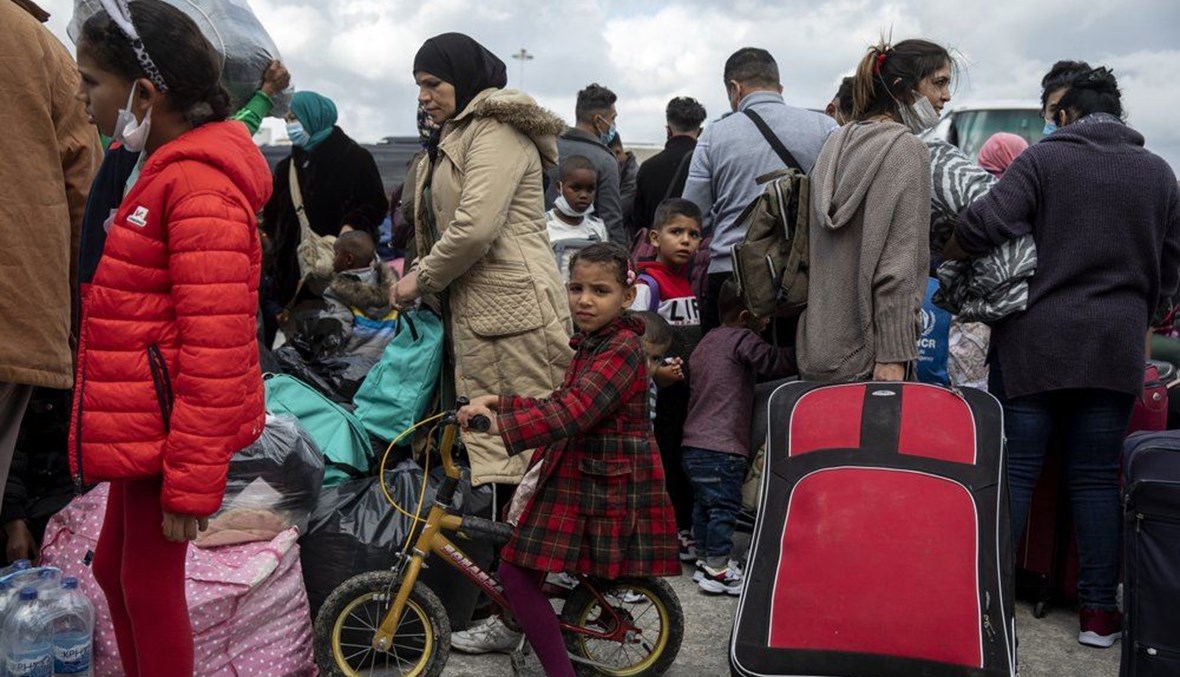 مهاجرون ينتظرون ركوب حافلات بعد نزولهم من سفينة في ميناء لافريو بجنوب أثينا (1 ت2 2020، أ ب). 