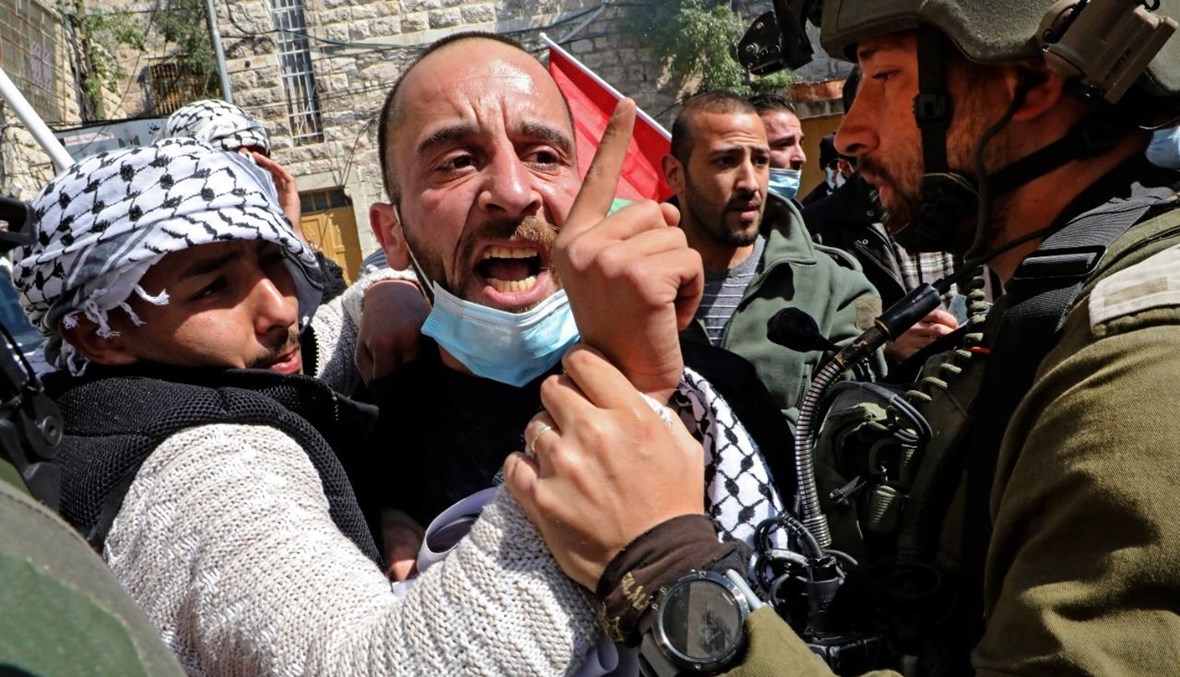 فلسطينيون يواجهون القوات الإسرائيلية خلال تظاهرة في مدينة الخليل بالضفة الغربية المحتلة، في ذكرى مذبحة المسجد الإبراهيمي عام 1994 (26 شباط 2021، أ ف ب). 