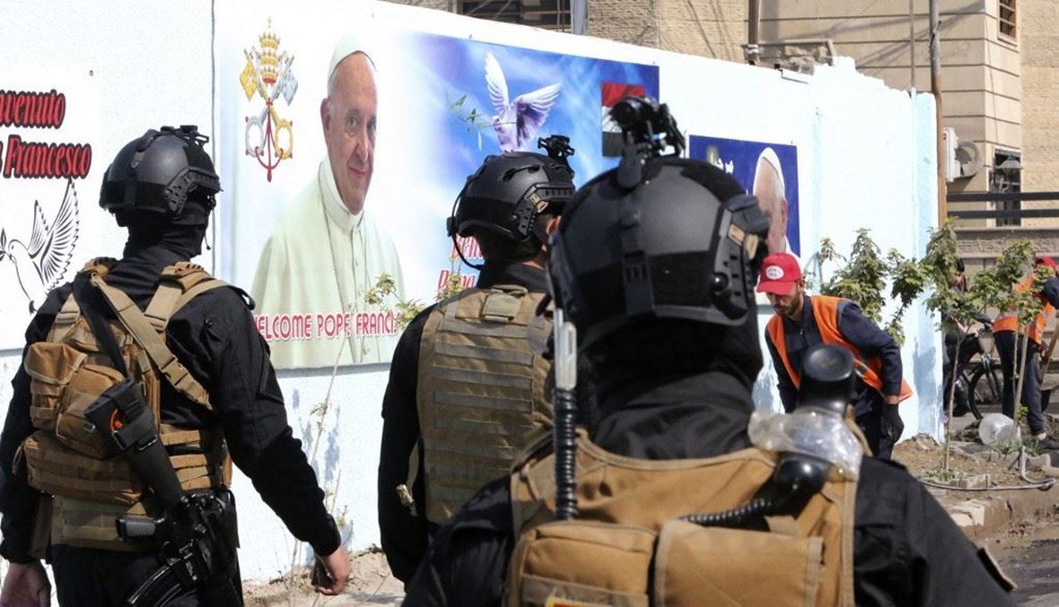 جنود عراقيون قرب كاتدرائية القديس يوسف في بغداد وبدت صورة للبابا فرنسيس أمس.   (أ ف ب)
