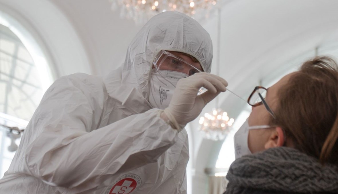 عامل صحي يأخذ مسحة أنفية من امرأة في مركز اختبار لكورونا في أورانجري بقصر شوينبرون في فيينا (4 شباط 2021، أ ف ب). 