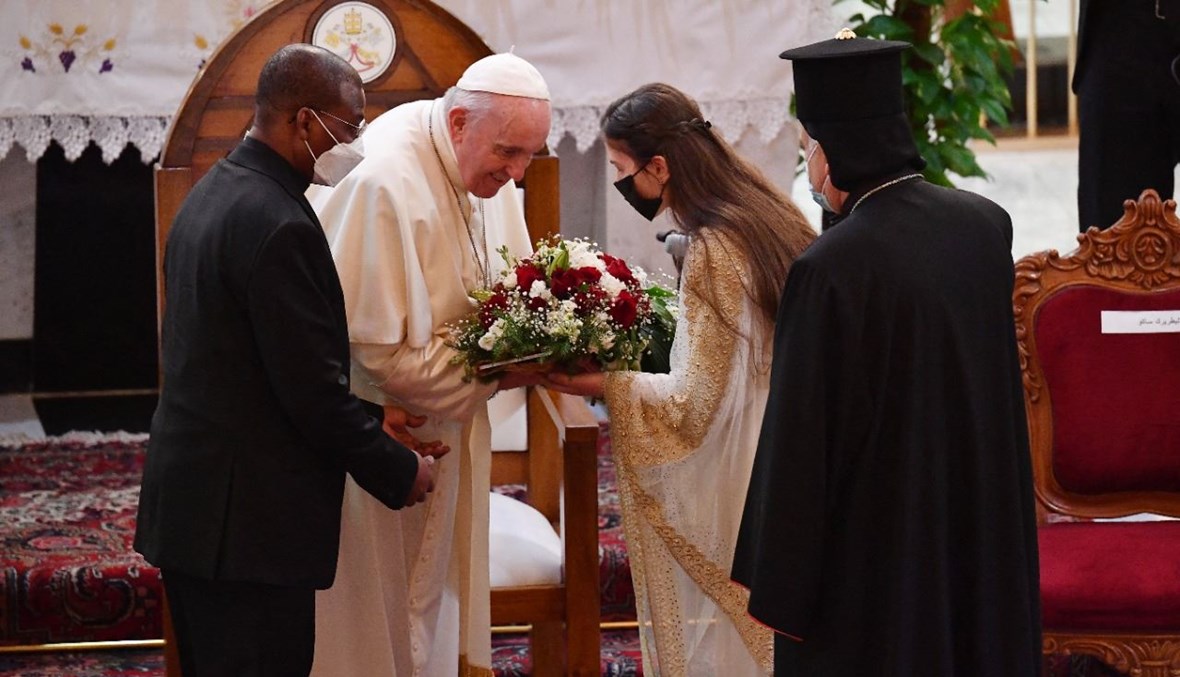 سيدة عراقية تقدم الى البابا فرنسيس باقة لدى وصوله إلى كاتدرائية سيدة النجاة في بغداد (5 آذار 2021، أ ف ب). 