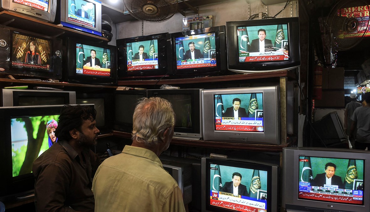 بائع أجهزة الكترونية يستمع لخطاب رئيس وزراء باكستان عمران خان (أ ف ب).
