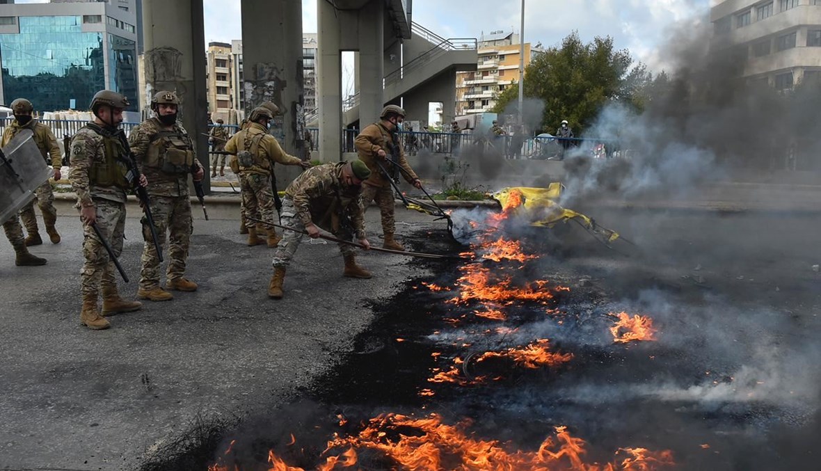 جنود في الجيش يعملون على ازالة الاطارات المحترقة لفتح الطريق تحت جسر الكولا- كورنيش المزرعة.(حسام شبارو)