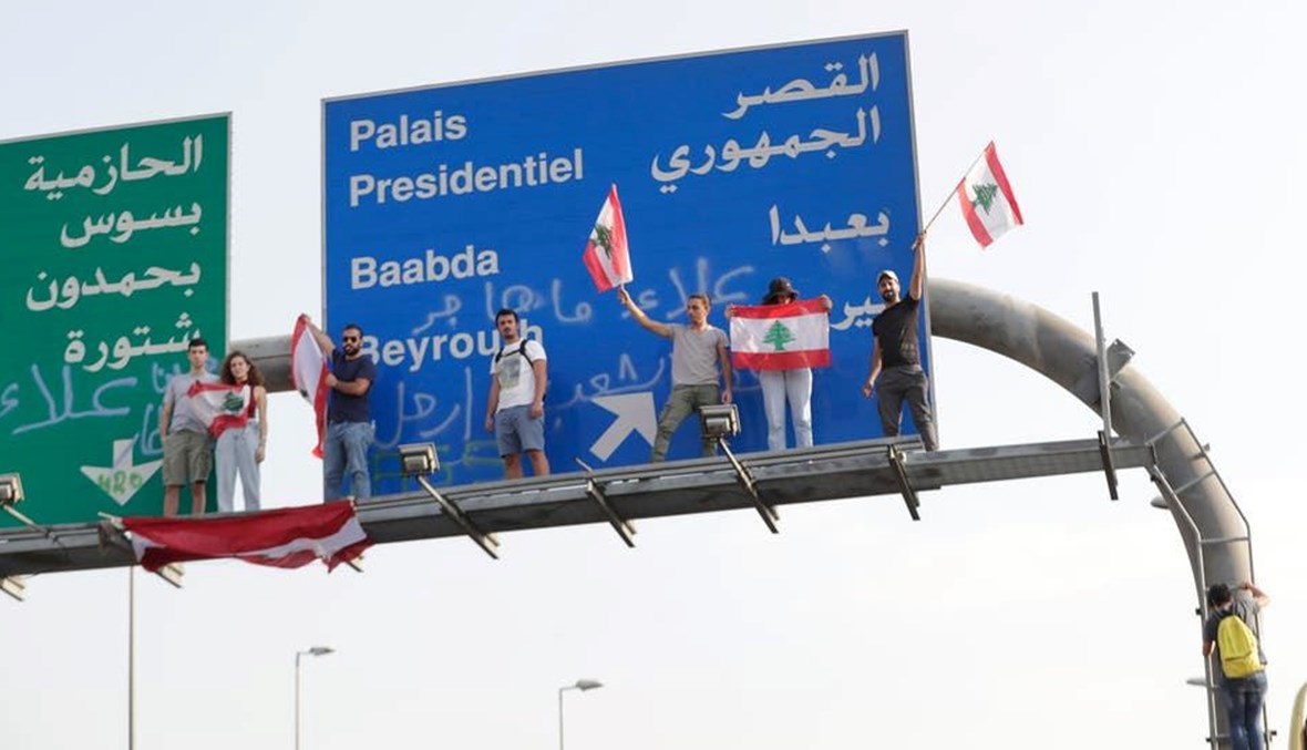 محتجون يقفون على لافتة مدخل الطريق المؤدي الى القصر الجمهوري