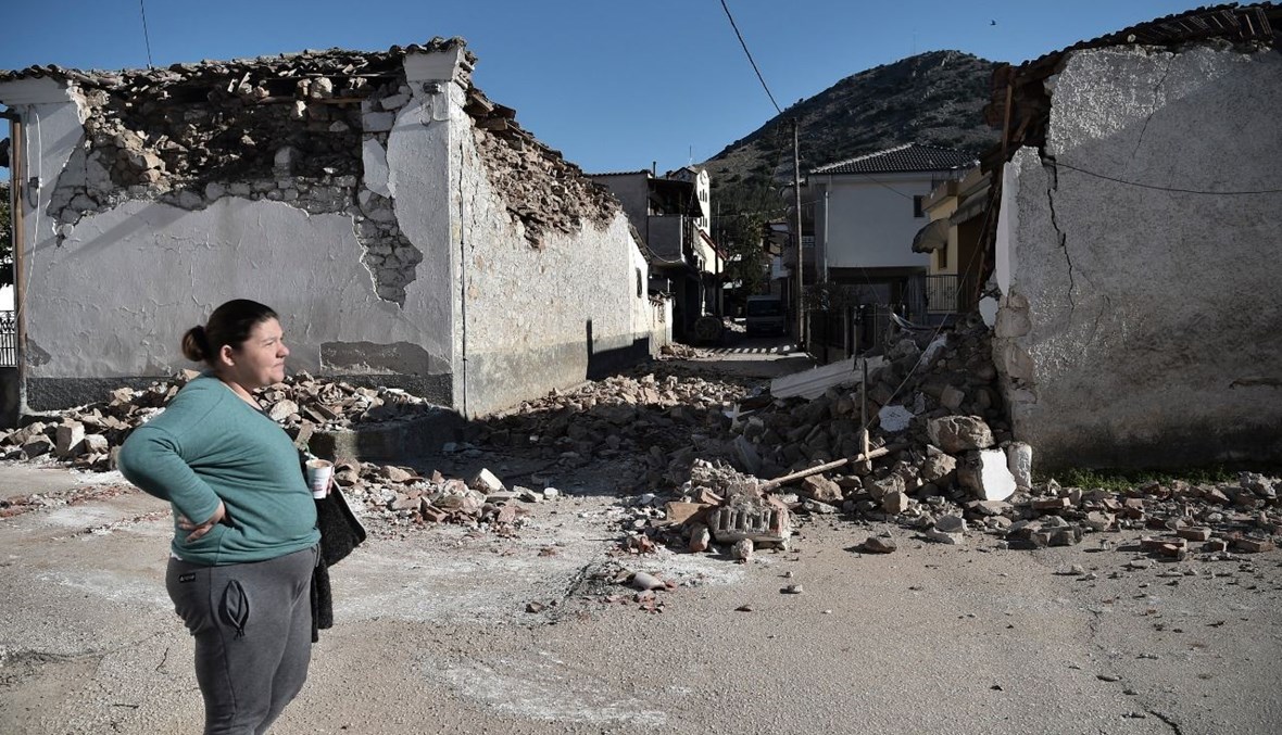 امرأة تقف بجوار أبنية قديمة تضررت في قرية دماسي، بعد زلزال قوي ضرب منطقة ثيساليا وسط اليونان (3 آذار 2021، ا ف ب). 