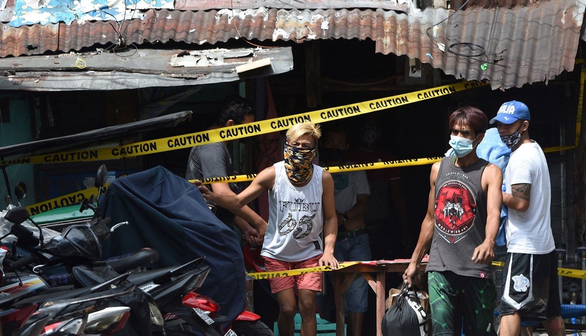 يقف السكان بجوار خط للشرطة عند مدخل منزلهم حيث تستعد الحكومة المحلية لفرض إغلاق في الحي في مانيلا، في 10 آذار 2021 (تعبيرية – أ ف ب).