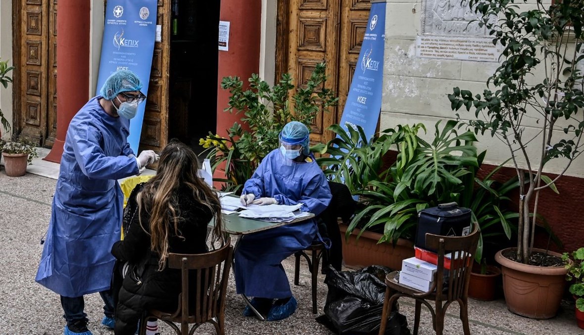 عاملون صحيون يجرون اختبارات سريعة مجانية لكورونا بالقرب من كنيسة في أثينا (14 آذار 2021، أ ف ب). 