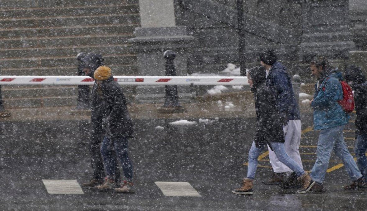 أشخاص يمشون تحت الثلوج في شارع كولفاكس في دنفر (13 آذار 2021، أ ب). 