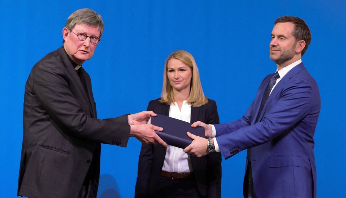 المحامي غيركي (الى اليمين) يسلم الى الكاردينال فولكي التقرير خلال مؤتمر صحافي في كولونيا غرب المانيا (18 آذار 2021، أ ف ب). 