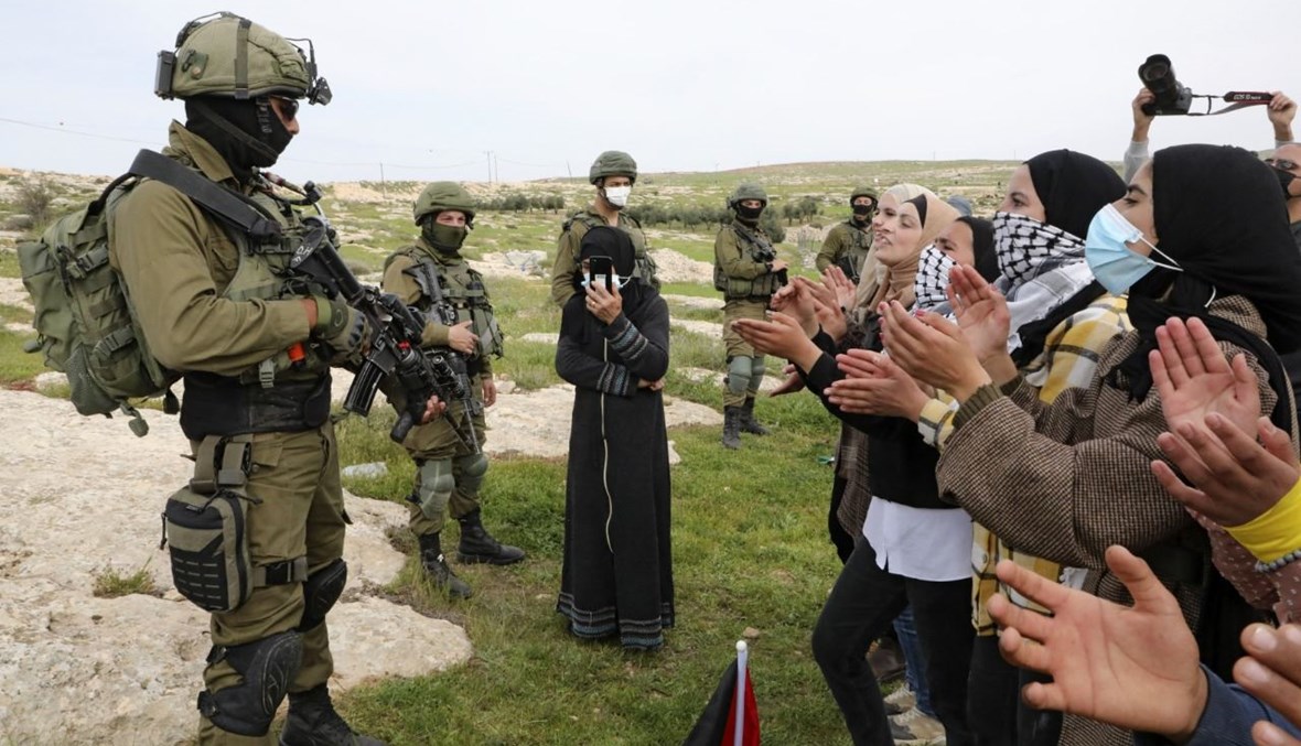 نساء فلسطينيات يرددن هتافات في مواجهة جنود إسرائيليين في خلال تظاهرة في قرية سوسيا جنوب بلدة يطا في الضفة الغربية المحتلة (14 آذار 2021، أ ف ب).  