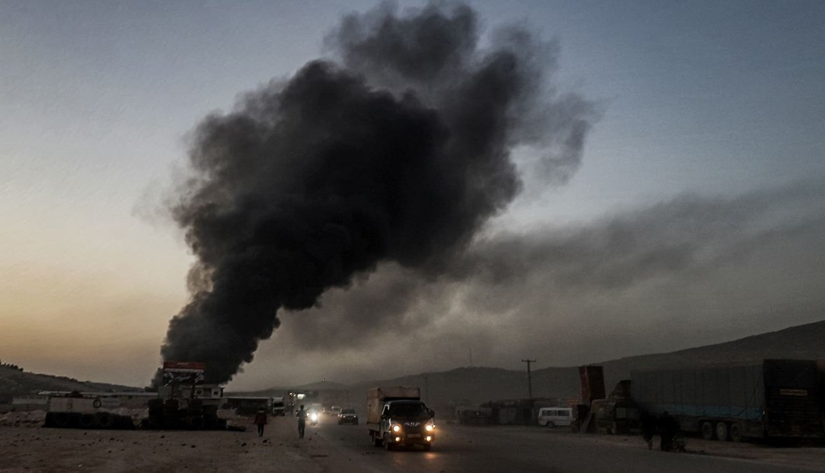 دخان يتصاعد من شاحنات ومركبات شحن احترقت في أعقاب غارات جوية على مستودع بالقرب من معبر باب الهوى الحدودي بين سوريا وتركيا في محافظة إدلب (21 آذار 2021، ا ف ب). 