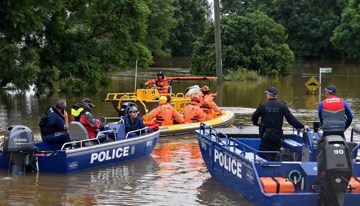 عناصر من أجهزة الطواريء يينقلون مساعدات إلى المتضررين من الفيضانات في ويندسور على الساحل الشرقي لأوستراليا أمس.   (أ ف ب)