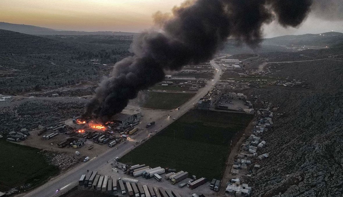 الدخان يتصاعد من شاحنات ومركبات شحن محترقة في أعقاب الضربات الجوية على مستودع بالقرب من معبر باب الهوى الحدودي بين سوريا وتركيا (أ ف ب).