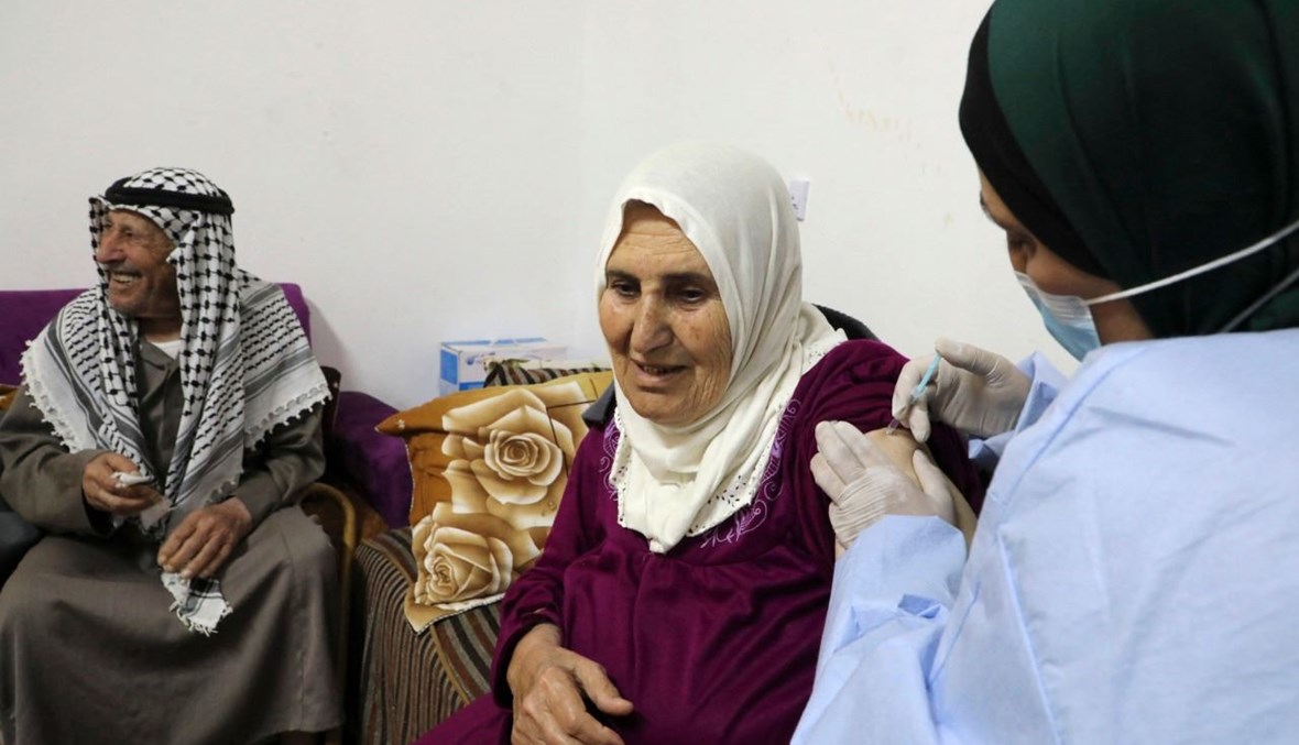امرأة فلسطينية تتلقى لقاح كورونا في منزلها في دورا بالقرب من الخليل بالضفة الغربية المحتلة (25 آذار 2021، أ ف ب). 