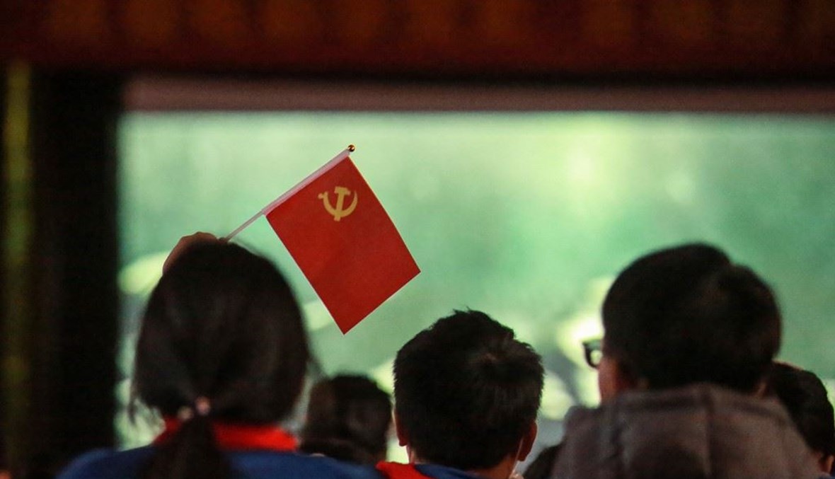  طالبة تحمل علم الحزب الشيوعي وهي تشاهد فيلم "تأسيس حزب" في يانغتشو شرقي الصين (أ ف ب). 