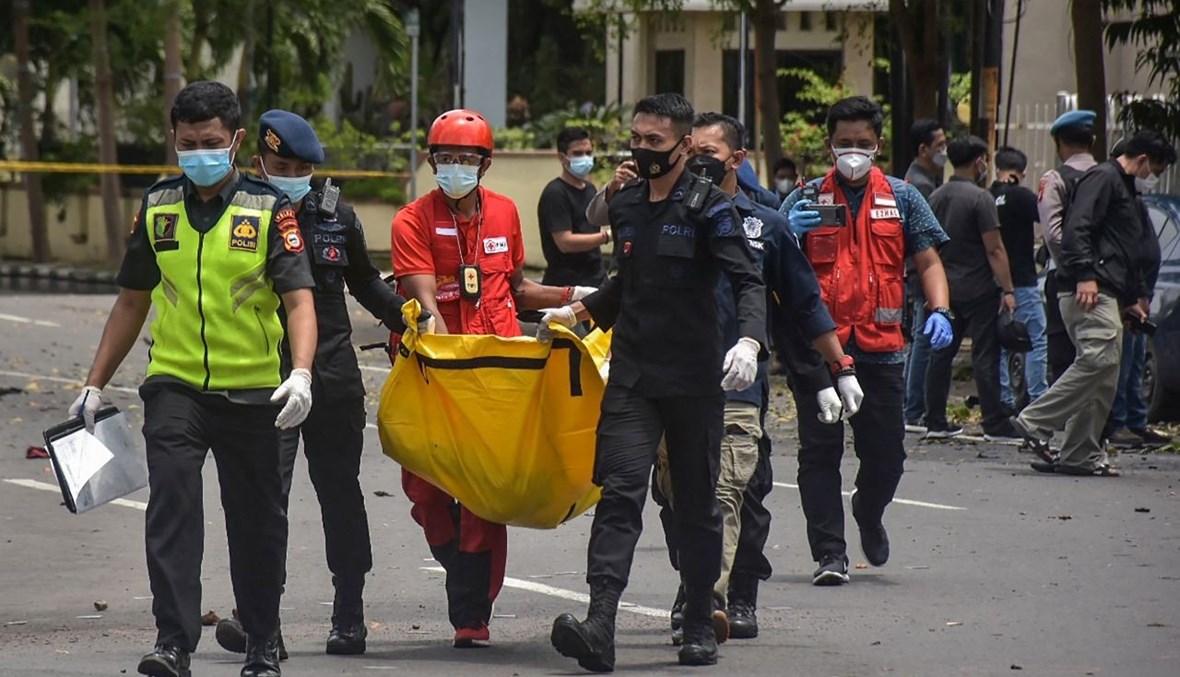 عناصر من الشرطة الإندونيسية يحملون كيسا وضع فيه رفات أحد الانتحاريين، خارج الكاتدرائية في ماكاسار (28 آذار 2021، أ ف ب). 