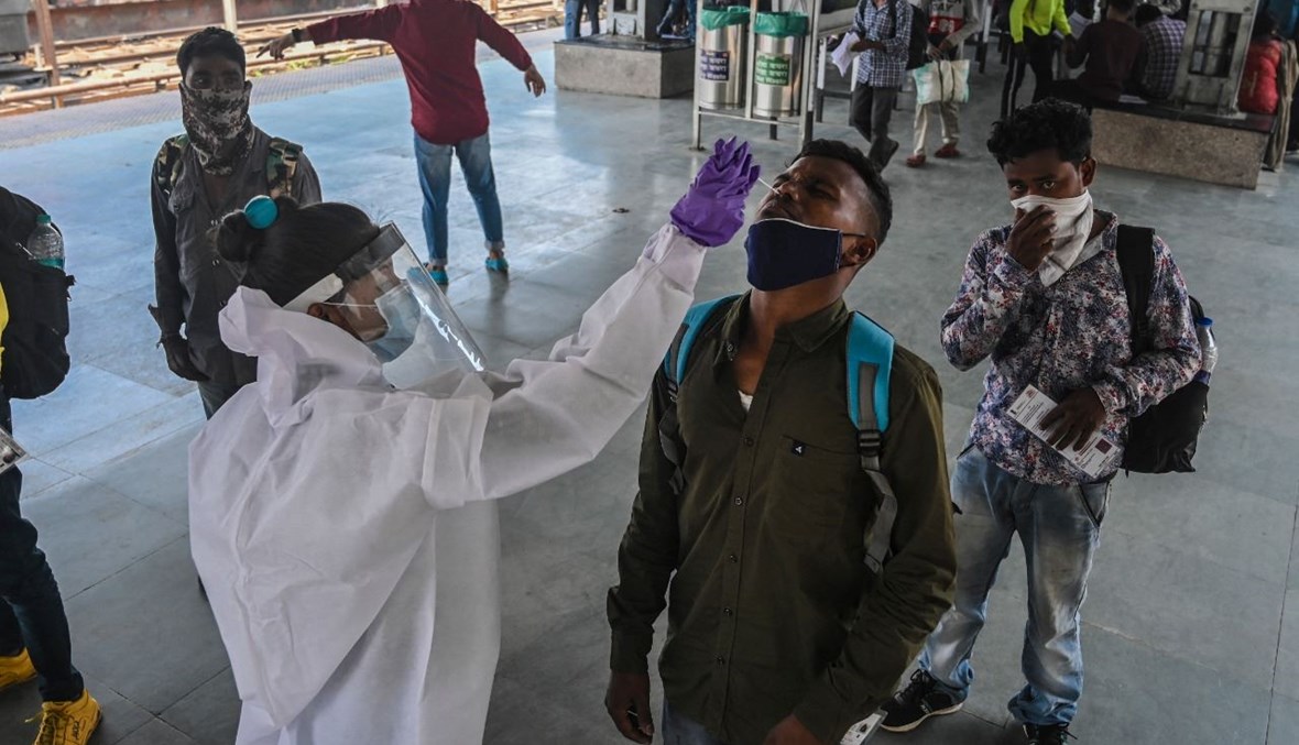 عامل صحي يأخذ مسحة أنفية من شخص في محطة قطارات في مومباي بالهند (29 آذار 2021، أ ف ب). 
