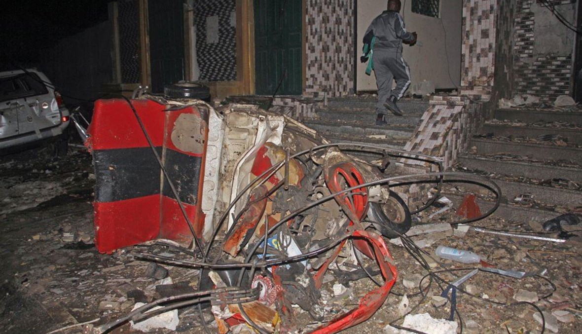 رجل يمر بالقرب من حطام سيارة في موقع انفجار في مطعم شعبي في العاصمة مقديشو بالصومال (5 آذار 2021، أ ب). 