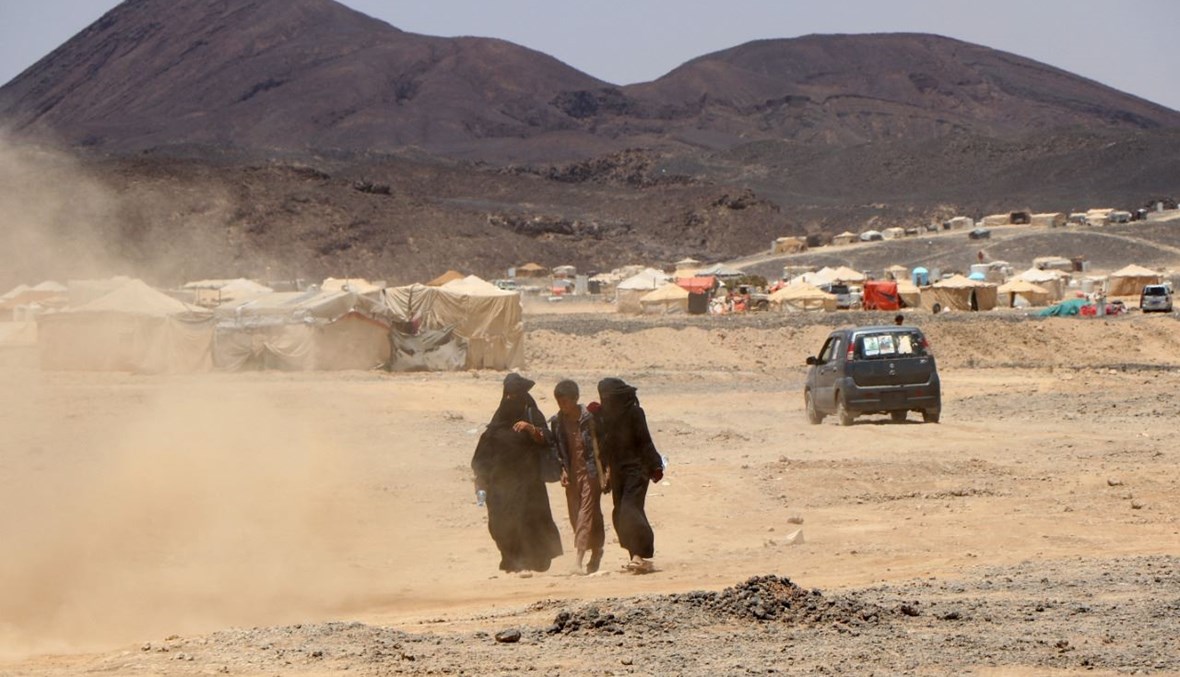 امرأة تمشي مع ولدين بالقرب من مخيم للنازحين على مشارف مأرب شمال شرق اليمن (28 آذار 2021، أ ف ب). 