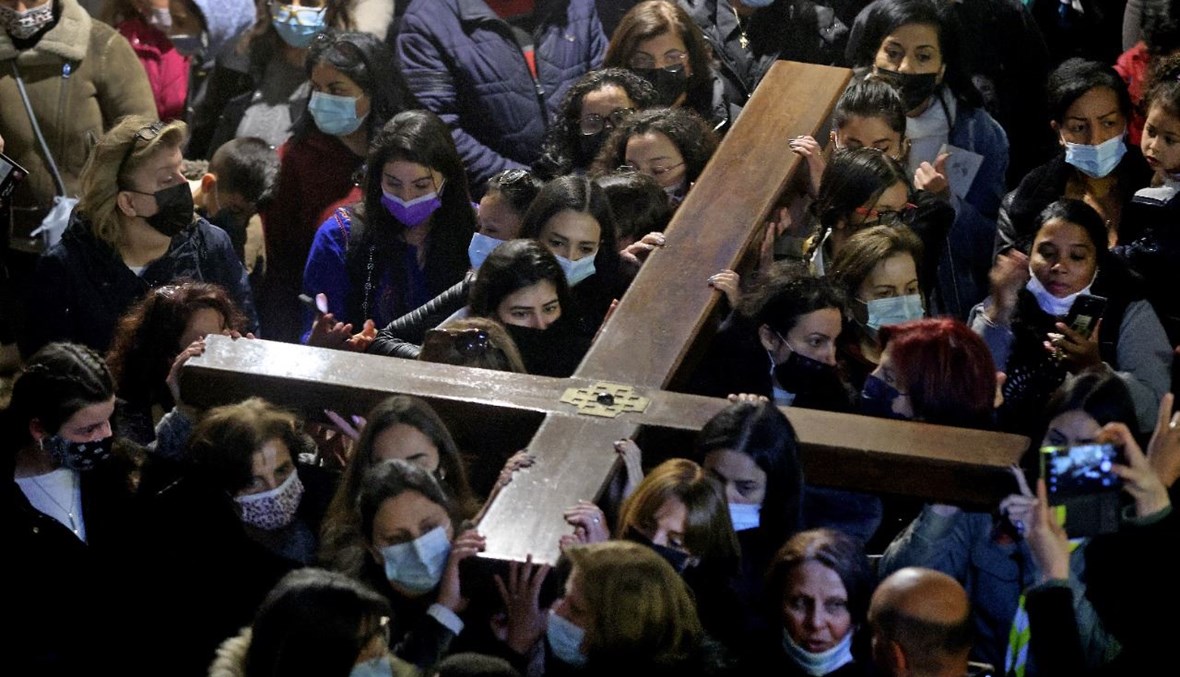 مؤمنون مسيحيون يحملون صليبًا خشبيًا لدى وصلوهم إلى كنيسة القيامة، خلال موكب الجمعة العظيمة على طول طريق الآلام  في البلدة القديمة بالقدس (2 نيسان 2021، ا ف ب). 