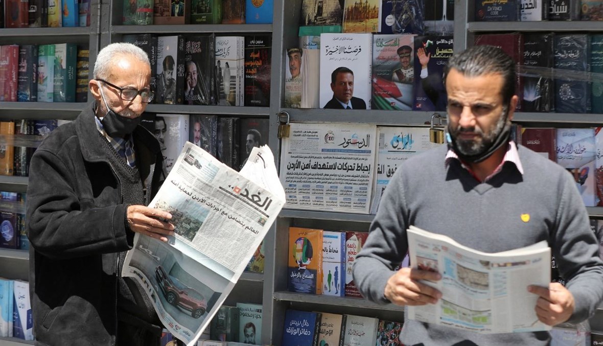 رجال أردنيون يقرأون الصحف المحلية أمام كشك في عمان (4 نيسان 2021، ا ف ب). 