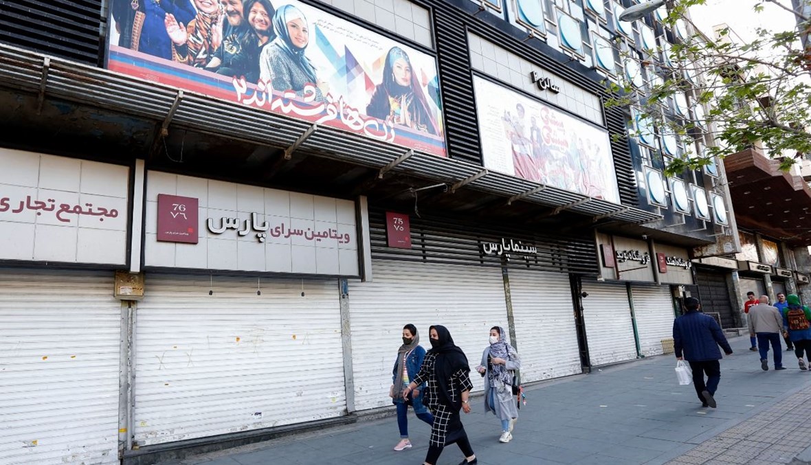 إيرانيون يمرون بالقرب من سينما مغلقة في طهران (29 آذار 2021، ا ف ب). 