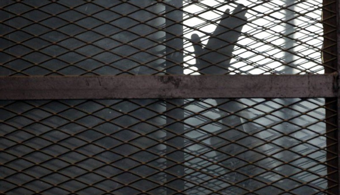 أحد أعضاء جماعة الإخوان المسلمين يلوح بيده خلال وقوفه في قفص المتهمين في قاعة محكمة بسجن طرة جنوب القاهرة (22 آب 2015، أ ب). 