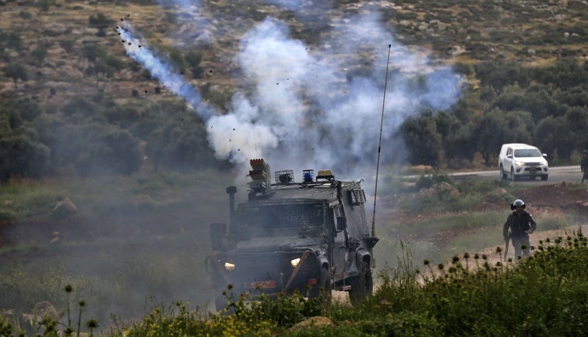 القوات الإسرائيلية تطلق الغاز المسيل للدموع على متظاهرين فلسطينيين خلال مواجهات في قرية المغير بالقرب من مدينة رام الله بالضفة الغربية المحتلة (2 نيسان 2021، أ ف ب). 