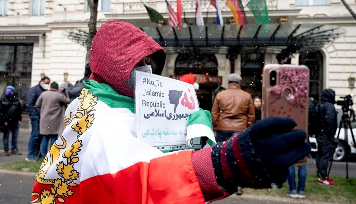 متظاهرة تحمل لافتة منددة بإيران أمام فندق "غراند" في فيينا حيث تدور المحادثات (أ ف ب).