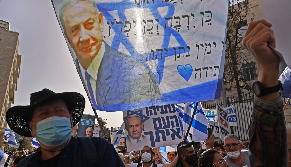 مشهد من الشارع الإسرائيلي ورفع علم يحمل صورة نتنياهو (أ ف ب). 