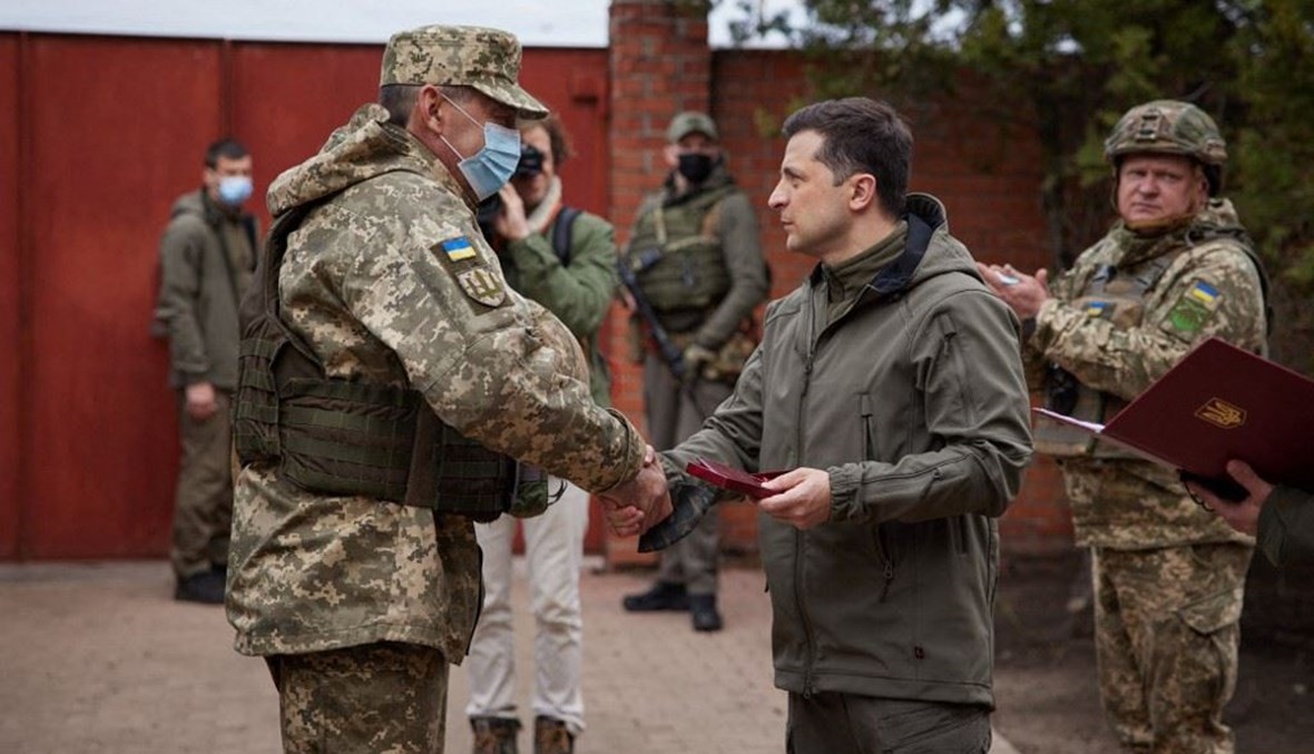 الرئيس الاوكراني فولوديمير زيلينسكي –الى اليمين- يصافح جنود على خط الجبهة في مدينة زولوتي بشرق أوكرانيا الخميس.  (أ ف ب)