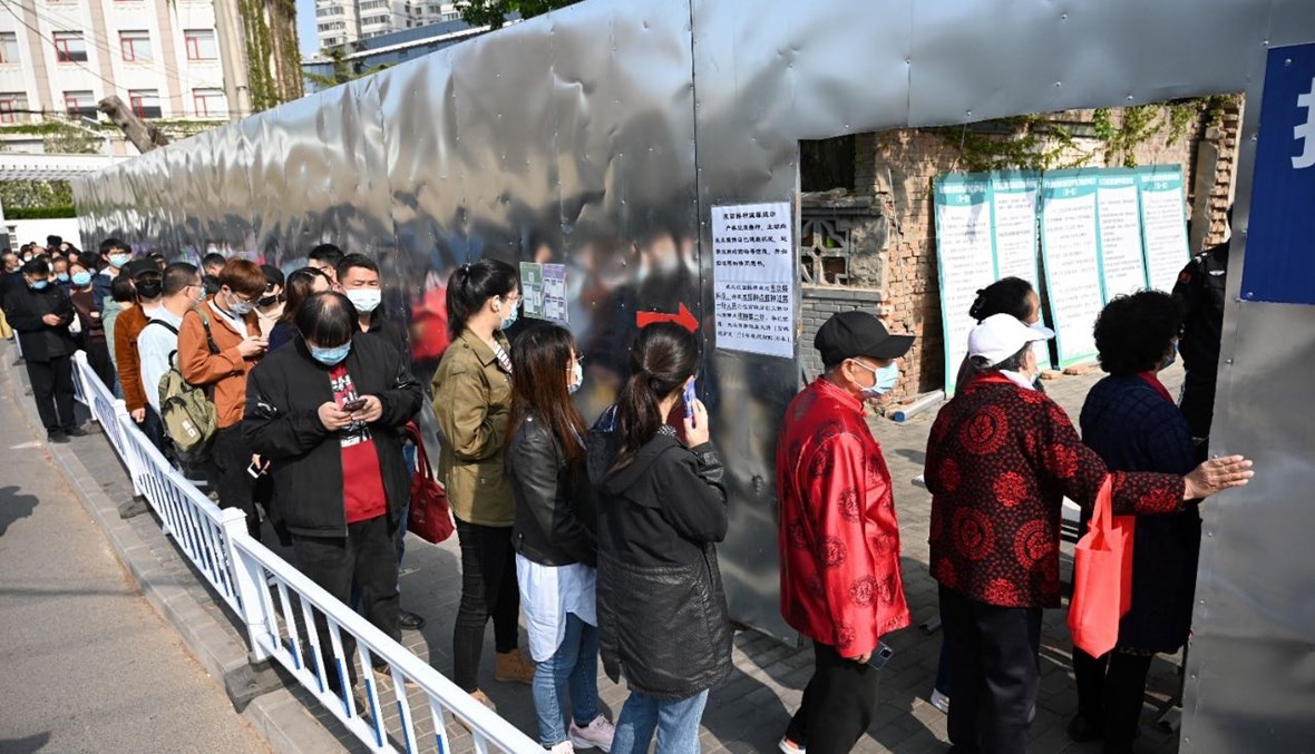 أشخاص ينتظرون بالصف امام مجمع سكني في بيجينغ، لتلقي لقاح كورونا (8 نيسان 2021، أ ف ب).
