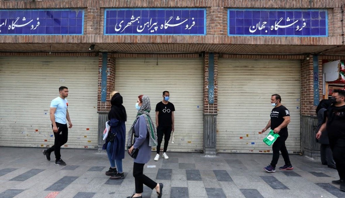 إيرانيون يمرون قبالة محال مقفلة في بازار طهران من جراء قيود كورونا.(أ ف ب)