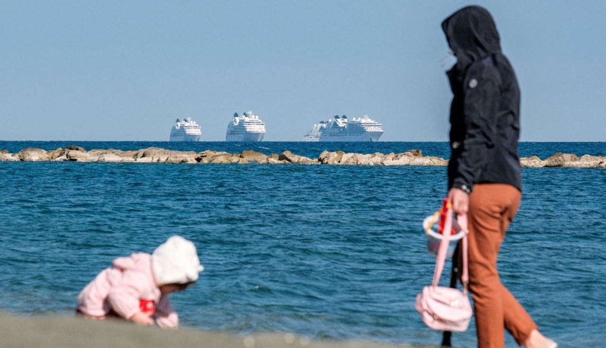 امرأة تراقب طفلاً يلعب على الشاطئ في مدينة ليماسول جنوب قبرص (30 آذار 2021، أ ف ب). 